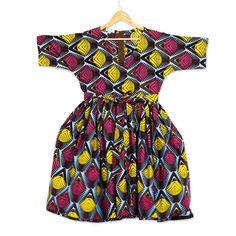 This brightly colored and boldly patterned dress is the original design of Ghana's Lydia Mawuenya Amedzrator. Crafted from 100% cotton in shades of burgundy sky blue and mustard the belted dress features short sleeves a V-neck and full skirt that hits at the knee. Cotton V-neck Dress With Graphic Print, Multicolor Knee-length Dress With Vibrant Print, Multicolor Printed Knee-length Mini Dress, Multicolor Short Sleeve Dress With Geometric Pattern, Multicolor Geometric Pattern Short Sleeve Dresses, Cotton Summer Dresses With Bold Print, Multicolor Cotton A-line Midi Dress, Summer Cotton Dresses With Bold Print, Summer Cotton Dress With Bold Print