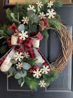 a wreath with snowflakes and evergreen leaves on the front door for christmas time