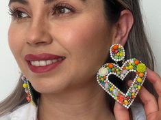 Add a modern and beautiful touch to your outfit with our charming heart earrings. Each pair is a masterpiece carefully hand-embroidered with calibrated beads and Czech crystals, ensuring quality craftsmanship. These Mexican earrings come in a range of vibrant colors, including yellow, orange and green, with delicate flowers in green and beige. They are the perfect choice for those looking for a unique and elegant piece of jewelry. Available in a variety of vibrant colors, these handmade earrings Trendy Dangle Heart Earrings For Wedding, Trendy Heart Dangle Earrings For Wedding, Trendy Heart Earrings For Wedding, Trendy Crystal Earrings For Wedding, Trendy Crystal Wedding Earrings For Pierced Ears, Trendy Heart Drop Earrings For Wedding, Trendy Wedding Heart Drop Earrings, Elegant Multicolor Heart Earrings For Gift, Elegant Multicolor Heart Earrings Gift