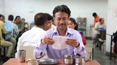 a man sitting at a table reading a paper