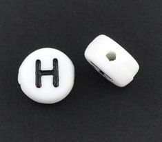 two white and black buttons with the letter h on each one, sitting on a black surface