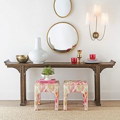 a table with two stools and a mirror on the wall