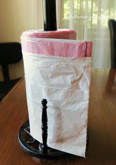 a white bag sitting on top of a wooden table next to a black candle holder