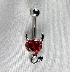 a red heart shaped navel ring with an arrow on the end and a silver nose piercing