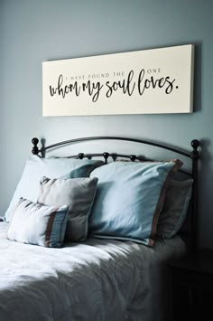 a bed with pillows and a wooden sign above it