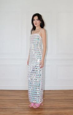 a woman in a sequin dress standing on a wooden floor with her hands behind her back