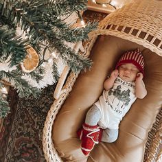 a baby is sleeping in a wicker chair next to a christmas tree and decorations