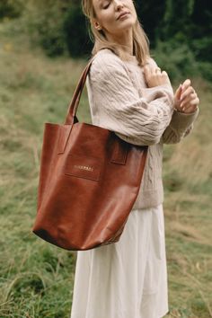 Simple, raw-finished leather bag in a minimalistic style. It is inconspicuous in size but has more than enough room to accommodate your whole world.  The bag has a magnetic closure, a small pocket for your smartphone and other essentials, and rolled handle. The bag is both stable and ductile. With time it becomes softer and gets deeper character.  The bag size measured in the position presented in the photo is: 35 cm (width), 38 cm (height), 18 cm (depth).  When measured laid flat the width amou Minimalist Brown Bucket Bag For Everyday Use, Minimalist Brown Bucket Bag For Everyday, Natural Leather Bag For Everyday, Minimalist Brown Soft Leather Shoulder Bag, Modern Brown Vegetable-tanned Bag, Everyday Brown Vegetable-tanned Bags, Everyday Bags With Leather Lining In Natural Color, Brown Minimalist Shoulder Bag With Leather Lining, Natural Leather Shoulder Bag For Everyday Use