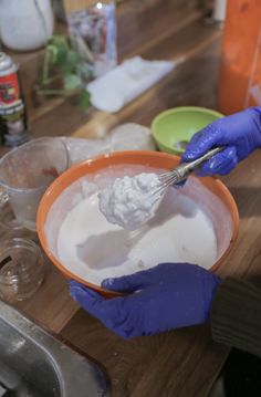 a person in blue gloves mixing something in a bowl