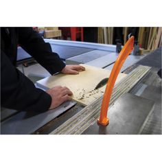 a person cutting something on a piece of wood with an orange object in the background