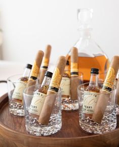 there are many bottles and glasses with cigars on the tray next to each other