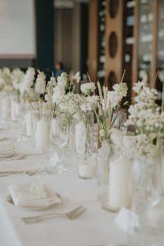 there are many vases with flowers in them on the long table at this wedding reception