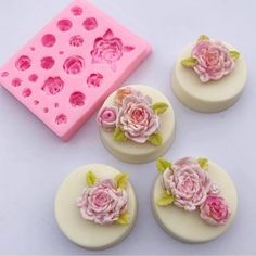 four pink roses are sitting on top of the cake molds