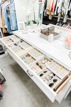 a white table topped with lots of drawers filled with rings and bracelets next to a mirror