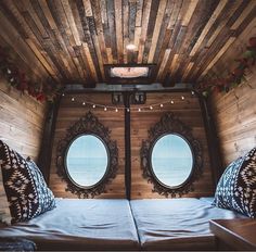 two round windows in the inside of a tiny house with wood paneling on the walls