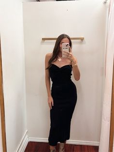 a woman in a black dress taking a selfie