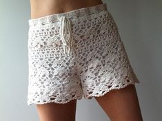 the woman is wearing white shorts with crochet on them