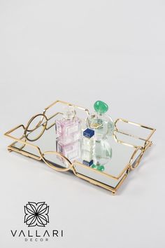 two small glass bottles sitting on top of a metal tray with gold trimmings