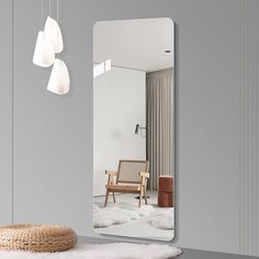 a large mirror sitting on top of a table next to a chair and lamp hanging from the ceiling