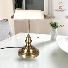 a white table with a gold lamp on it