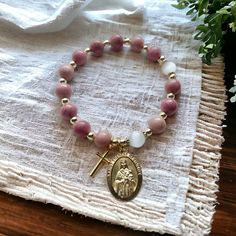 Featured here is a stretch rosary bracelet made with 8mm pink rhodochrosite stone beads, adorned with a gold tone crucifix and a Saint Therese medal.   It fits adult wrist size 6.5 to 7.25 inches. This item is gift ready! It ships with a drawstring pouch for storing. Occasion: Confirmation/baptism. Other available beads (Message us for a custom order!) -Blue aventurine -Bamboo Leaf Agate -Pink Quartz St. Therese of Lisieux, Pray for Us! Thanks for checking our online shop! Part of our earnings g Spiritual Gold Beaded Rose Quartz Bracelets, Pink Stretch Bracelet With Natural Stones For Meditation, Pink Spiritual Gemstone Beads Stretch Bracelet, Spiritual Pink Stretch Bracelet For Healing, Pink Natural Stones Stretch Bracelet For Meditation, Pink Round Beads Stretch Bracelet For Meditation, Spiritual Pink Hand-strung Stretch Bracelet, Pink Spiritual Rosary Bracelet With 8mm Beads, Adjustable Pink Rosary Bracelet For Healing