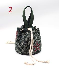 a small black and white bag with red flowers on the front, tied up to it's side