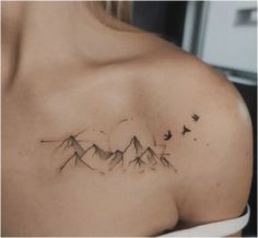 a woman's shoulder with mountains and birds tattoo on her left side ribcage