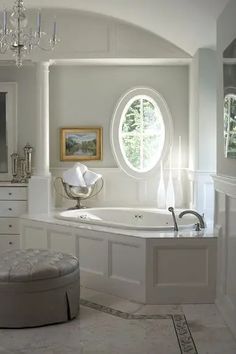 a large bathroom with an oval window and chandelier