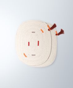 two round rugs with tassels on top of each one in the shape of a circle