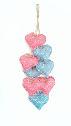 four hearts hanging from a string on a white wall with polka dotty fabric and twine