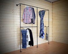 clothes are hanging on the rail in front of a wall mounted coat rack with three rails