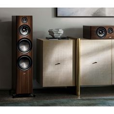 two speakers sitting next to each other in front of a cabinet with a painting on the wall