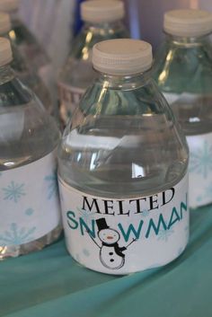 several bottled water bottles sitting on top of a blue tablecloth covered table with snowman stickers