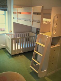 a white bunk bed sitting next to a baby's crib in a bedroom