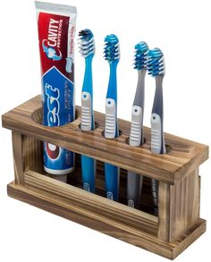 four toothbrushes in a wooden holder with toothpaste