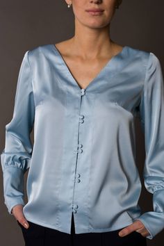 "A beautiful satin blouse featuring button front closure, long sleeves with cuffs, and a v-neckline. - v-neckline - fabric button front closure - long sleeves with cufffs - shift silhouette Color: light blue Fabric: Viscose - 30, polyester - 65%, elastane - 5%. Our model wears size US 8 and is 171cm/5'6\" tall. You may feel free choosing the size. Just send us your measurements (bust, waist, hips, height). We will define your correct size. SIZE CHART XS __ EU 34 __ US 4 bust: 31,5\" | 80 cm wais Spring V-neck Blouse With Button Cuffs, Elegant V-neck Top With Button Cuffs, Fitted V-neck Shirt With Button Cuffs, Satin Top With Button Closure, Solid Satin Top With Button Closure, Satin Button-up Top With Buttons, Fall Satin Blouse With Button Closure, Satin Button-up Blouse, Elegant Satin Tops With Button Cuffs