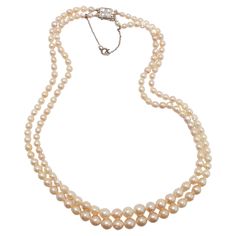 Dating to approximately 1940, this luxurious strand of luminous, gleaming nearly-antique cultured pearls is so fine in quality it rivals -and in some ways surpasses- that of natural, uncultured pearls. Composed of 155 creamy white graduated cultured Akoya pearls. measuring from 3mm to just above 8mm, this double-strand necklace features an exquisite 18K clasp set with four small, beautiful old-cut diamonds. The clasp bears marks from France. These pearls hail from the early days of the cultured pearl farming industry. As such, they were allowed to remain in the cold seawater for a longer period of time than modern Akoya pearls. The resulting pearls have thick nacre that gives them the luminous look of natural pearls, which are solid nacre. The pearls also have surface blemishes and imperfe Vintage Akoya Pearl Necklace For Formal Occasions, Double Strand Pearl Necklace For Formal Occasions, Formal Double Strand Pearl Necklace, Classic Double Strand Pearl White Necklace, Classic Double Strand Pearl Pendant Necklace, Classic Double Strand Pearl Necklace With Pendant, Vintage Akoya Pearl Necklace, Formal Antique Pearl Drop Necklace, Vintage Akoya Pearl Drop Necklace