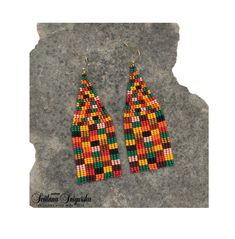 a pair of colorful beaded earrings sitting on top of a rock