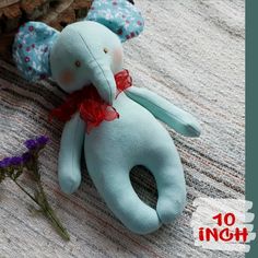 a blue stuffed elephant laying on top of a table next to a purple flower bouquet