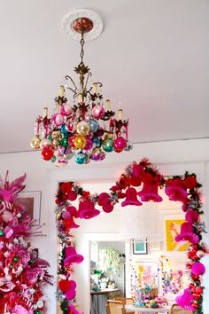 a chandelier hanging from the ceiling in front of a mirror with pink and red decorations