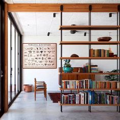 a bookshelf filled with lots of books in a living room next to a sliding glass door