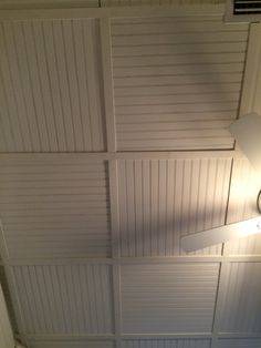 a ceiling fan mounted to the side of a wall in a room with white paneling