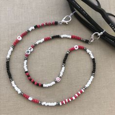 Best selling glasses chain! This Ohio State inspired chain shows off your football pride! It is made with red, black, silver, white and fun beads. Add a FREE PERSONALIZATION to make it yours or an original gift, i.e., Ohio, OH-IO, OSU, Buckeyes, etc. If no personalization is specified, no letters will be used. The photo is personalized. Securely holds your sunglasses, readers, or mask in style or connect the ends to wear as a necklace. See shop for many other color patterns to choose from. Beading and patterns vary as no 2 chains are alike! Message for specific customization - fees will apply.  Size: 27"  Made in Las Vegas. Visit our other store: MADELV.com See other Ohio listings or search "Ohio" https://falabco.etsy.com/listing/1031110013 https://falabco.etsy.com/listing/1172536686 https Customized Red Casual Jewelry, Customized Casual Red Jewelry, Casual Customized Red Jewelry, Casual Red Customized Jewelry, Eyeglasses Chain, Osu Buckeyes, Black Beaded Jewelry, Personalized Football, Eyeglass Chain