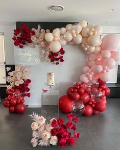 balloons and flowers are arranged on the floor in front of a wall with an arch