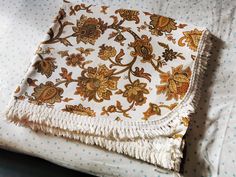 a white and gold blanket laying on top of a bed