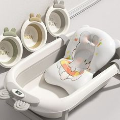 a baby seat with an elephant design on the front and side, next to three cups