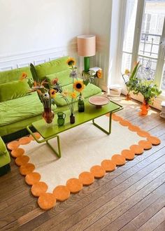 a living room with green couches and orange rugs on the wooden flooring