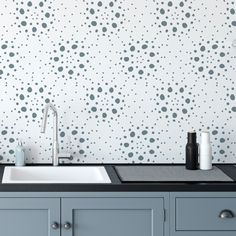 a kitchen sink sitting under a faucet next to a wall with dots on it