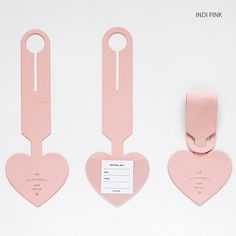 three heart shaped tags are attached to the back of a pink luggage tag with a name tag on it