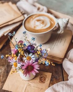 a cup of coffee and some flowers on a table